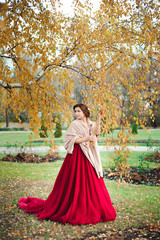 Fototapeta premium beautiful girl in a red dress in the autumn forest