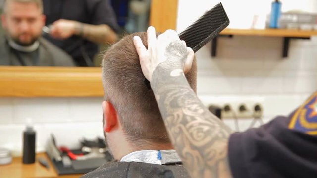 Barber cuts the hair of the client with clipper at barbershop.