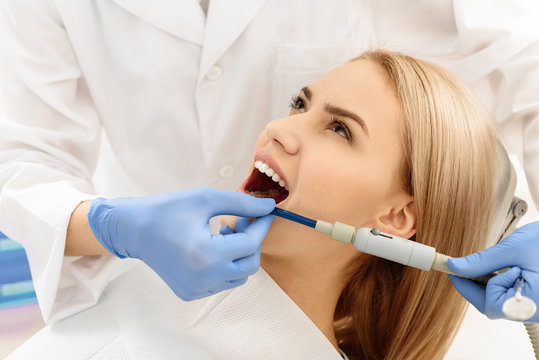 Dental surgeon putting pump in mouth of woman
