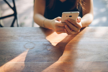 Hand of woman using smartphone on old wooden table,Space for tex