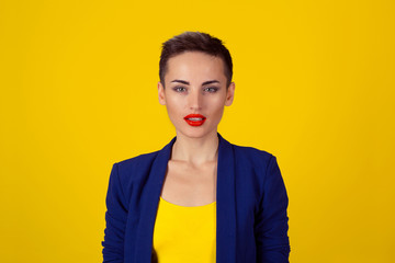 Happy serious young beautiful happy business woman looking at you isolated yellow background....