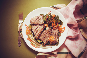 veal steaks with spinach and chilli salad on white plate