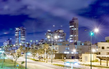 Night landscape resort town with tropical palm trees and skyscrapers