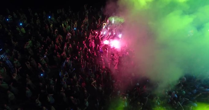 Aerial view of crowd with red signal flare dancing on music festival