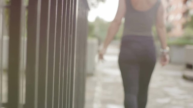 silhouette of woman walking by touching the bars of a gate