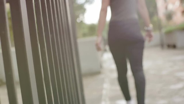 woman's hand running over the bars of a gate