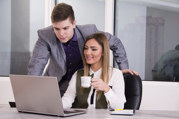 Business couple working together. Businessman and businesswoman on a laptop. Surfing the net.