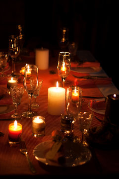 Festive composition with candles and plates. Table decoration. A beautiful table setting, red table cloth, tablecloth in a cage. Christmas dinner. A white plate with a nice napkin on the table