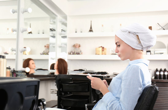 Young woman with towel on her head sitting in salon