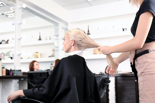 Hairdresser holding wet blonde's hair at salon
