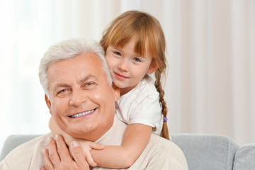 Happy grandfather with granddaughter on couch