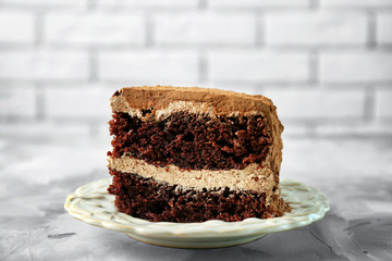 Slice of tasty chocolate cake on brick wall background