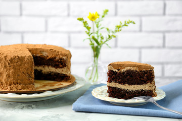Slice of tasty chocolate cake on napkin against brick wall background