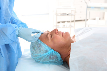 Fototapeta premium Surgeon hands with scalpel near senior man face