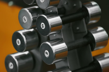 Rack with dumbbells in gym, close up view