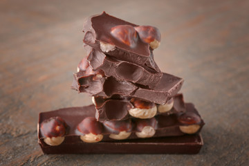 Broken chocolate pieces with hazelnut, on wooden background