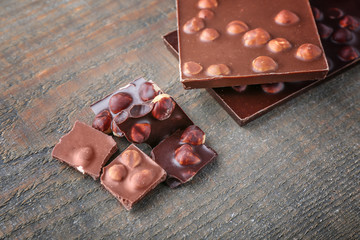 Broken chocolate pieces and bars with hazelnut, on wooden background