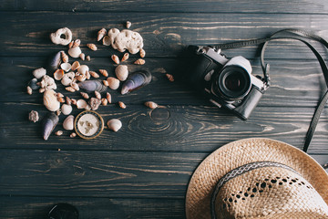 travel background. Men's style hat, compass, seaShell and camera on a wooden background