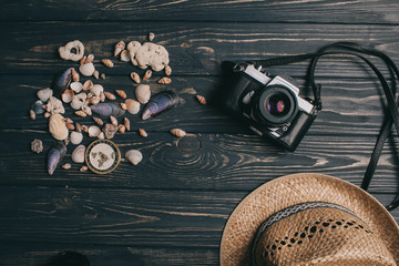 travel background. Men's style hat, compass, seaShell and camera on a wooden background