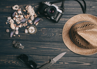 travel background. Men's style hat, compass, seaShell and camera on a wooden background