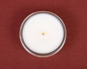 Soy candle in glass jar on red fabric background