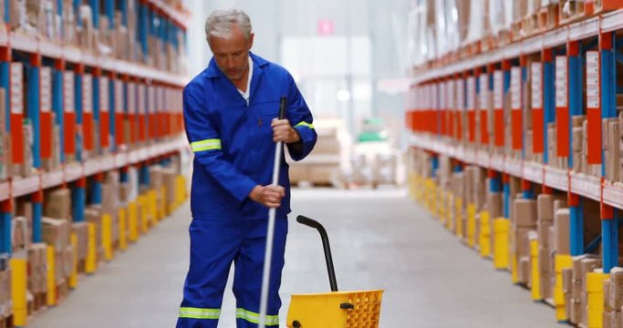 Male warehouse worker moping floor