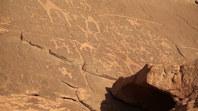 Ancient rock paintings, petroglyphs depicting humans and camels on the rock in Wadi Rum desert, Hashemite Kingdom of Jordan