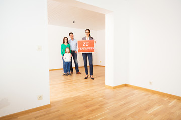 Realtor In Empty Apartment, Holding 'zu Verkaufen' Sign