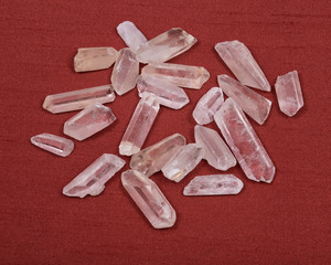 Clear quartz crystal on red fabric background