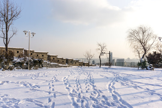 naksan park stone wall covered in snow with the view of the city in the back. Taken in Seoul, South Korea