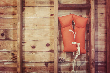 Old orange life jacket hanging in a boat house