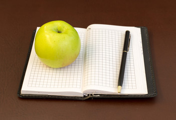 pen and apple on the background of notebook