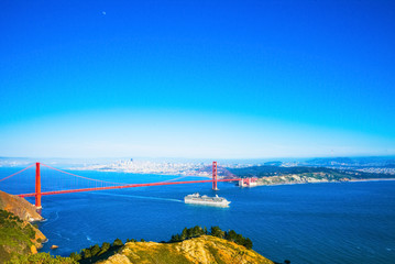 A white cruise ship passing under the Golden Gate Bridge in San Francisco, California, USA.  Daytime.