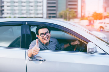 Young asian handsome man smiling and showing thumbs up in his ca