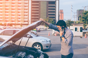Young asian handsome man standing by the Broken Down car