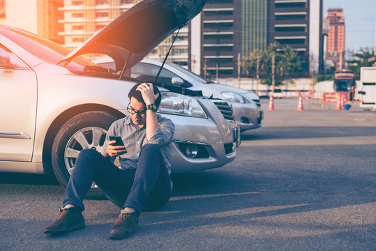 Young asian handsome man sitting by the Broken Down car