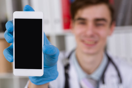 Doctor holding a smartphone in hand. Demonstrates display. The image depth of field.