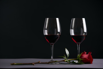 Two wineglasses with red rose on a dark background. Valentine's day theme concept