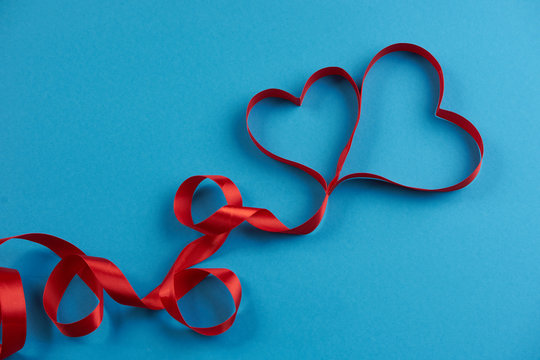 Ribbons shaped as hearts on blue background, In love card concept. Valentine's day theme.