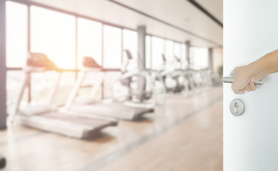 man hand opening white door to fitness or gym room interior
