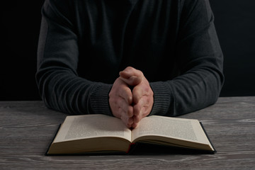 praying hands on a book on wooden table. Religion concept