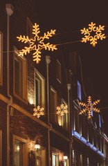 Street in a Christmas night in an old European town. Building decorated for Christmas. Winter snowless night in an old street. Old town with illuminations and decorations for New Year holidays.