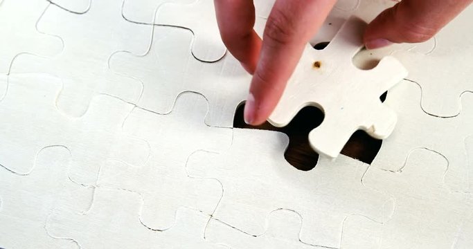 Womans placing missing piece in Jigsaw puzzle