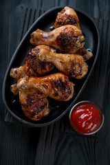 Grilled chicken legs with sauce served in a cast-iron frying pan