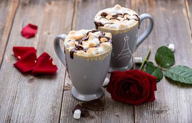 S'mores drink. Two mugs of hot chocolate with marshmallows on a wooden table. Cocoa. Rose petals. Valentine.