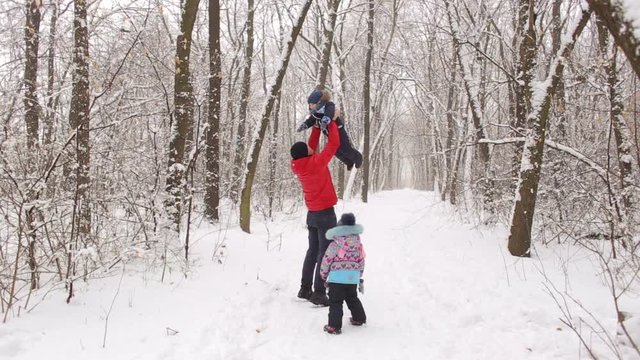 Dad with two children playing in a winter forest.