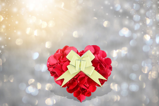 Rose petals heart shape with golden gift bow on background bokeh