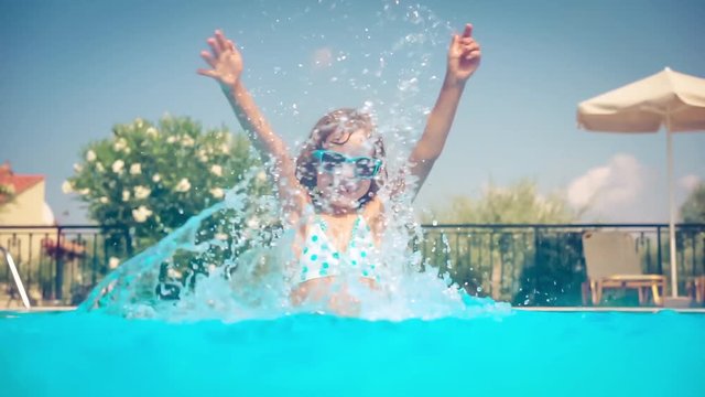 Happy child playing in swimming pool. Girl having fun outdoors. Summer vacation and holiday concept. Slow motion
