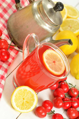 Fruit cherry tea with slice of lemon in mug, old teapot and cherries