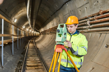 Surveyor with theodolite level at underground railway tunnel construction work